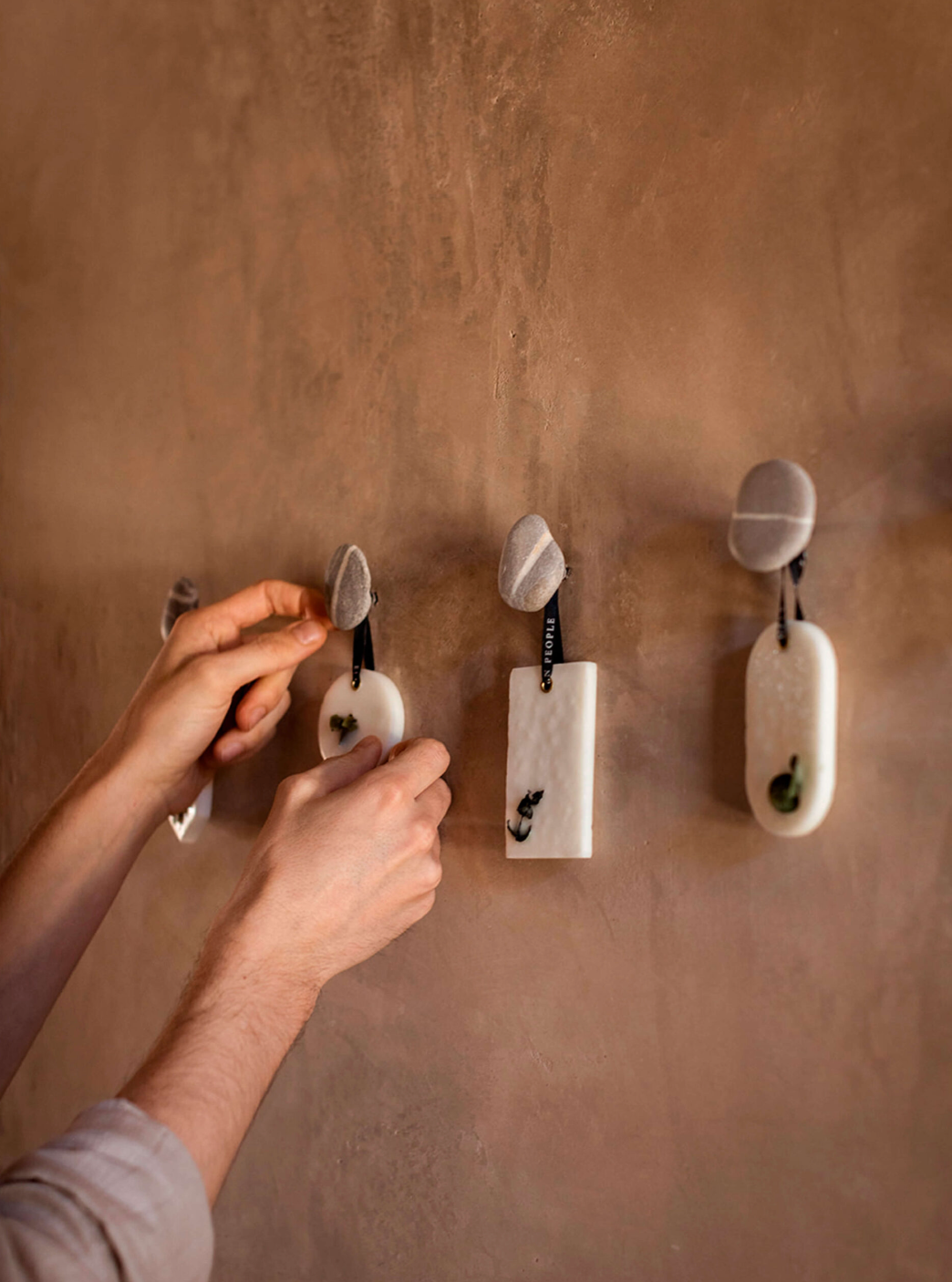 Person using a hook on a textured wall with other hooks already attached.