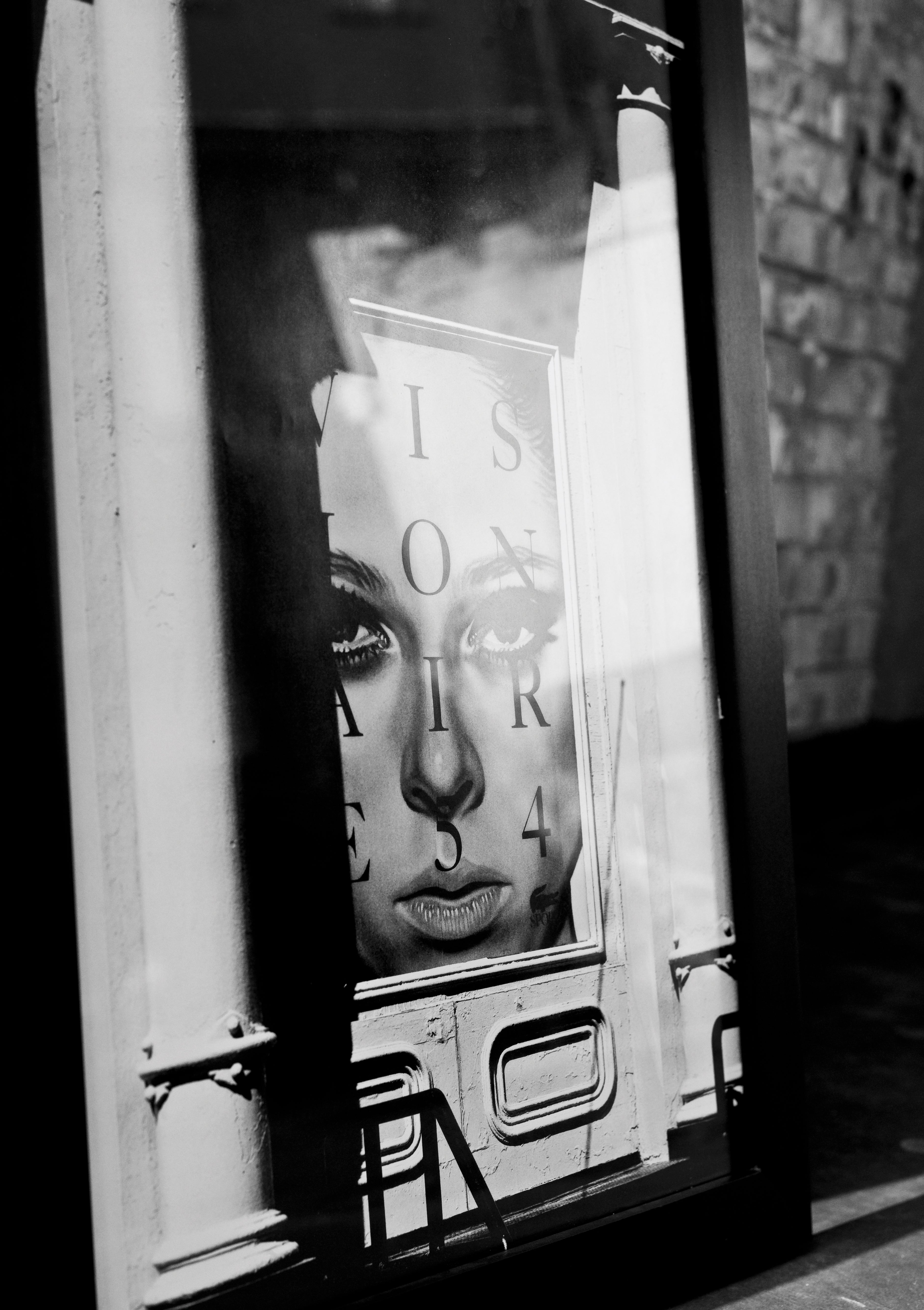 Black and white poster of a woman's face with text on a wall.