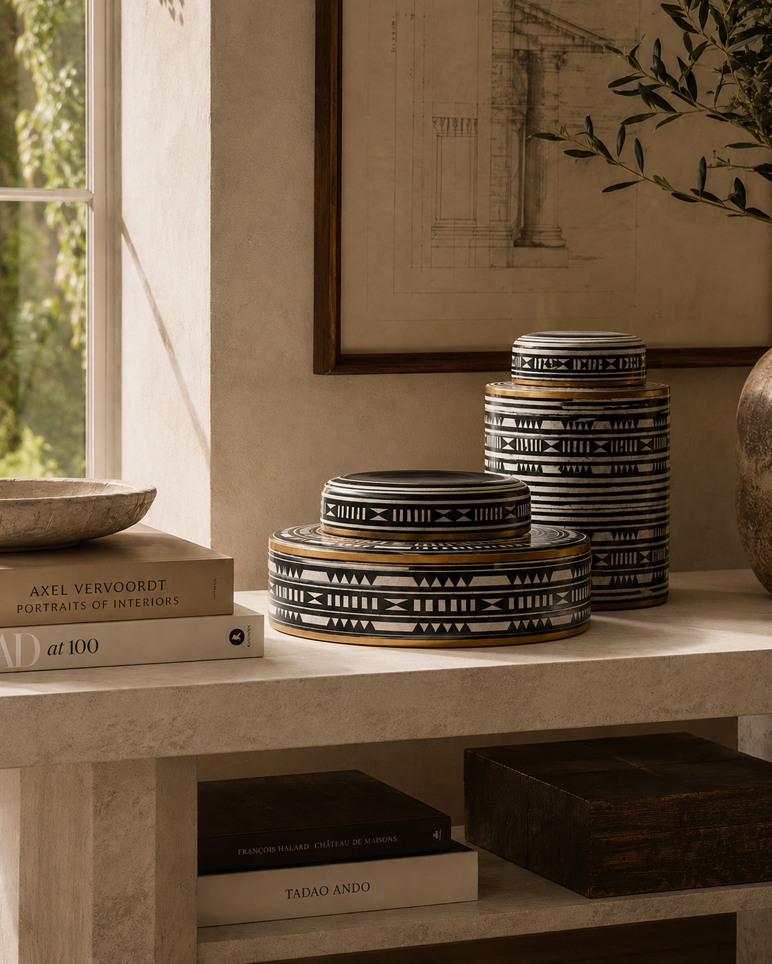 extra large ceramic ginger jar with black and white geometric patterns and gold accents, styled on a stone shelf next to books and a framed print.