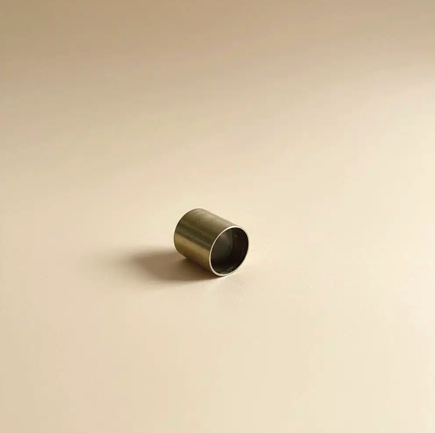 Bronze cylindrical object on a beige background