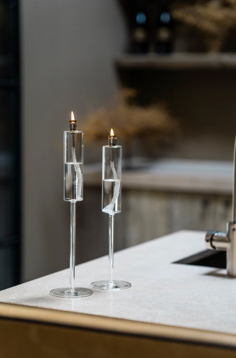 Two modern candle holders on a surface with a blurred background