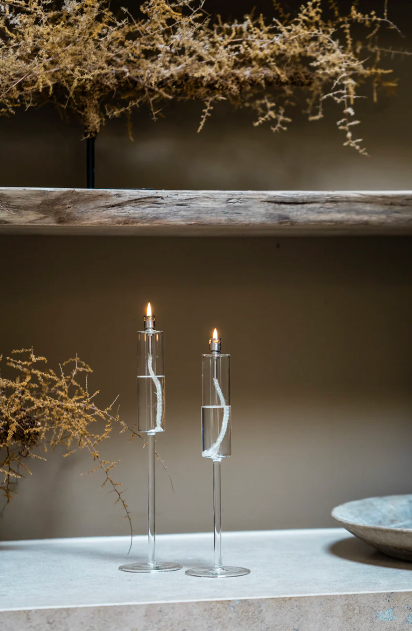 Two glass candle holders with candles on a neutral background