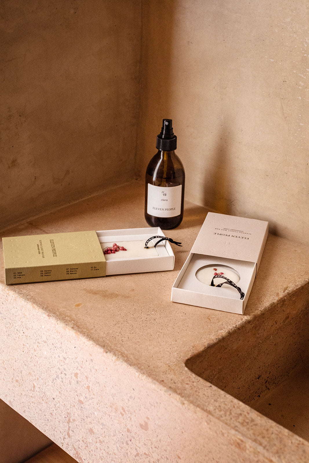 Bottle of skincare product on a textured surface with scented wax bar boxes and items.