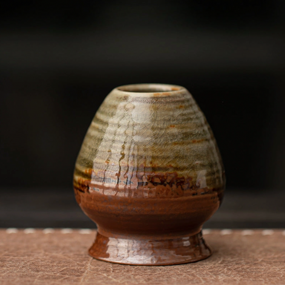 Ceramic vase with striped pattern on a dark background