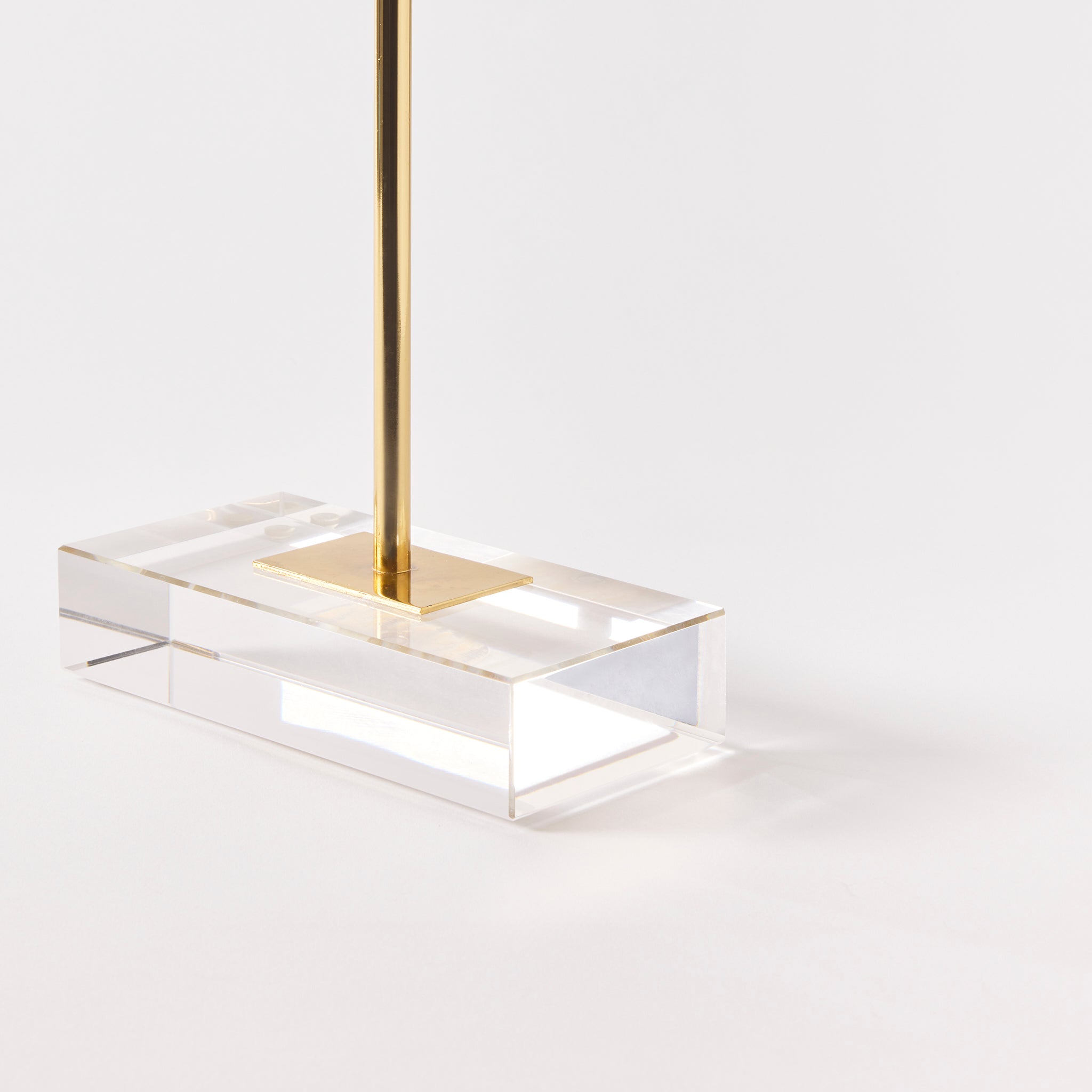 Modern pendant light with gold fixture and clear acrylic base on a white background