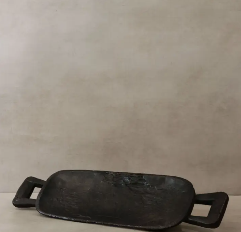 Black rectangular metal pan with handles on a beige background