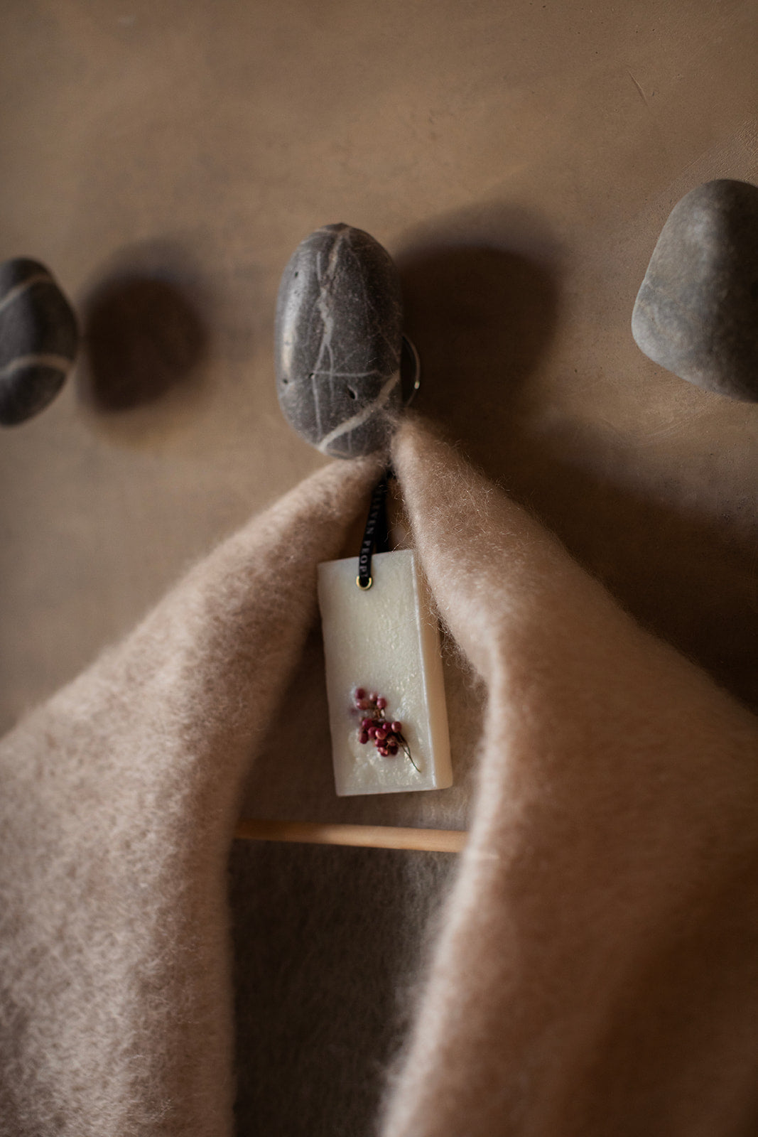 Close-up of a stone with a tag attached, draped over a textured surface.
