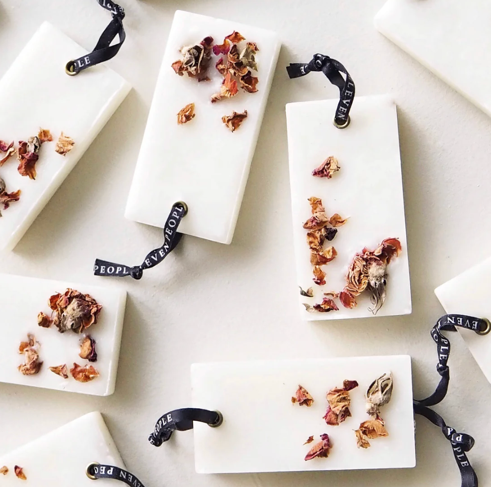 White soap bars with dried flowers and black ribbons on a light background