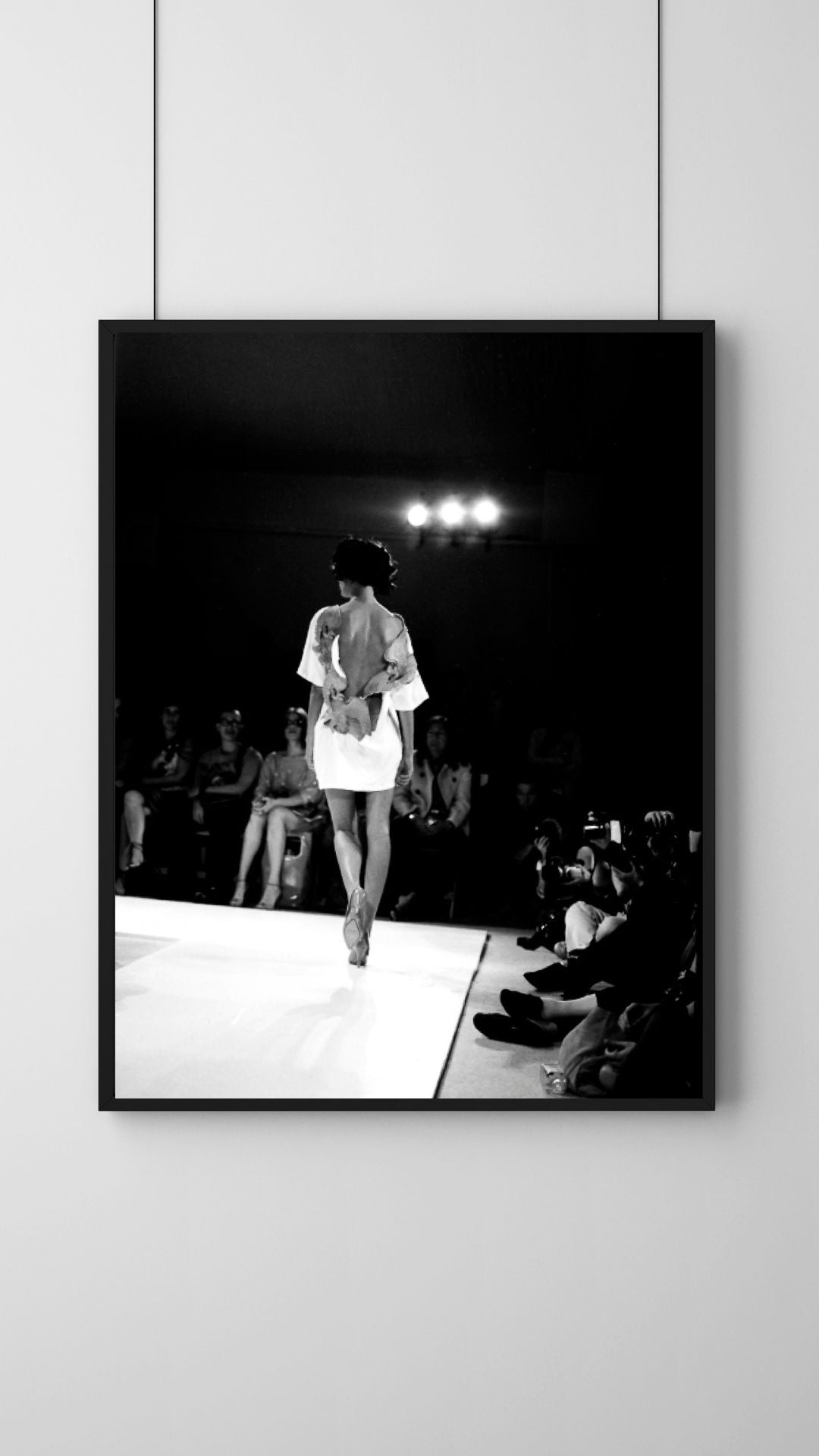 Framed black and white photograph of a model walking on a runway.