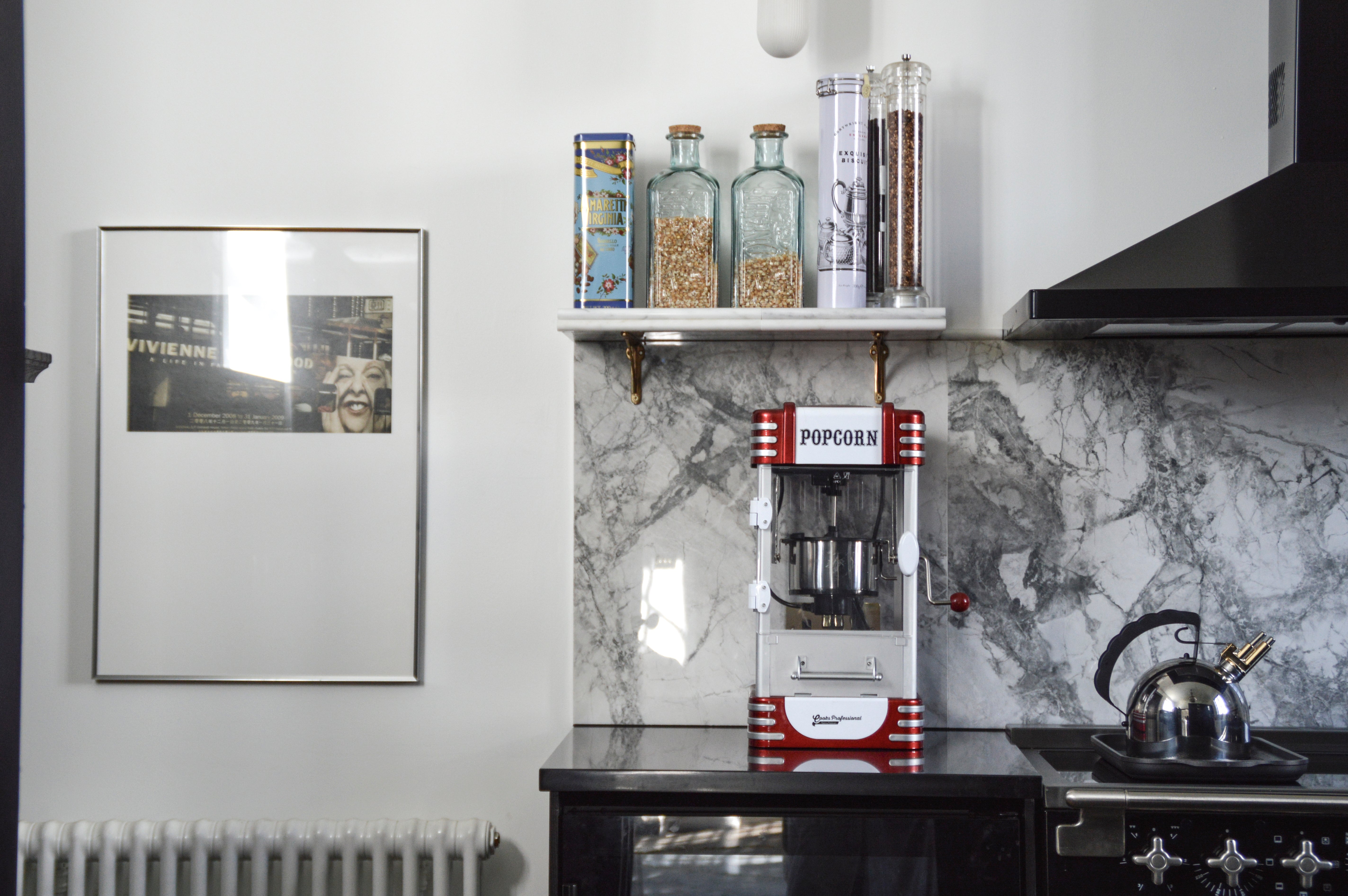 Popcorn machine on a kitchen counter with a marble backsplash.