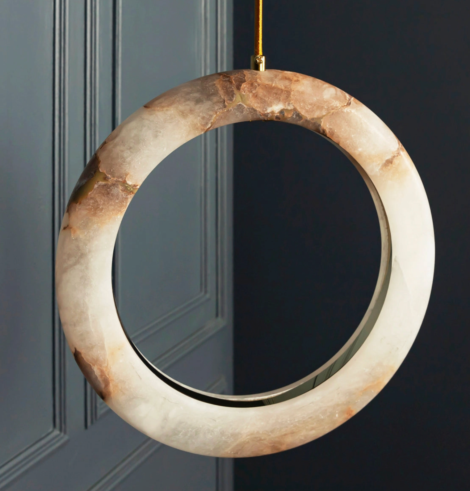 Decorative circular mirror with a marble-like finish hanging on a dark door.