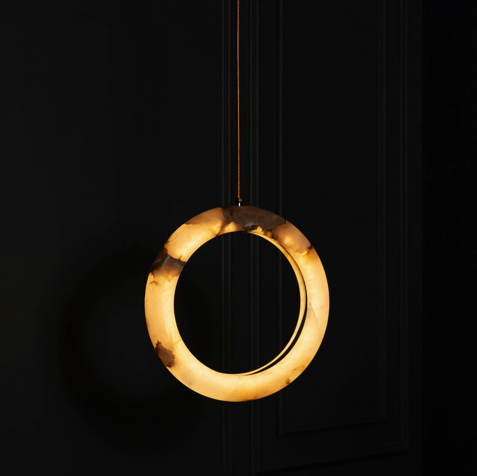 Circular pendant light with a warm glow on a black background
