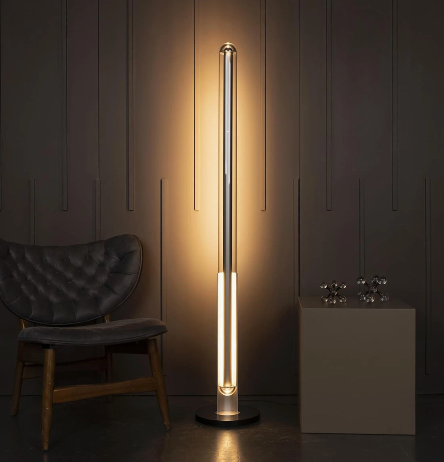 Modern floor lamp in a dimly lit room with a chair and decorative items.