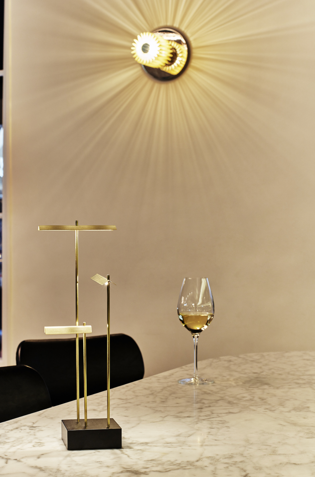 Decorative wall light fixture with a glass of white wine on a marble surface.