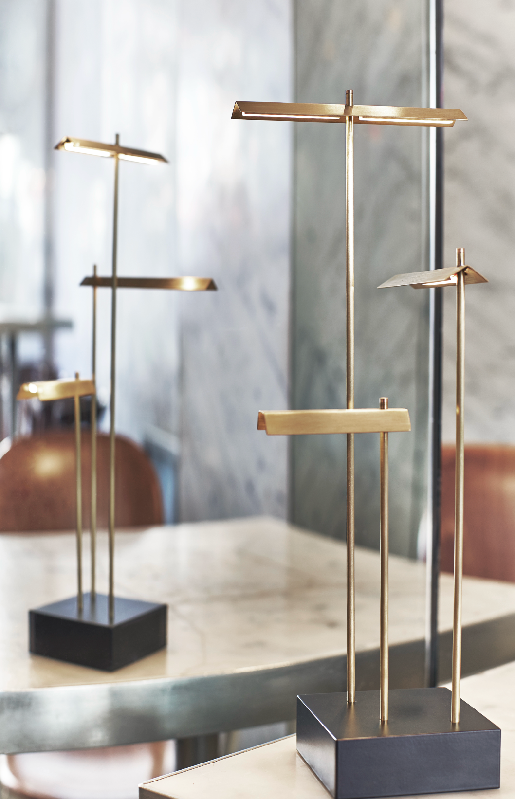 Set of three modern gold and black decorative stands on a reflective surface.