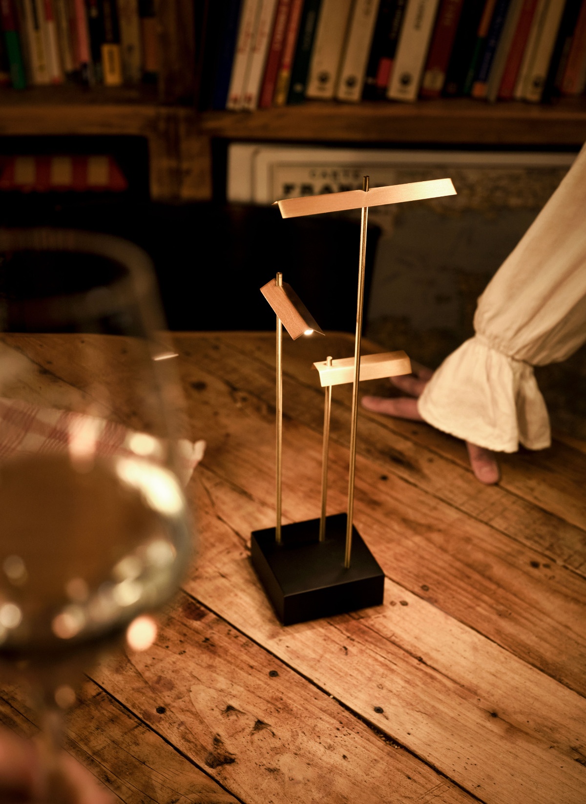 Small music stand on a wooden floor with a glass of wine and books in the background