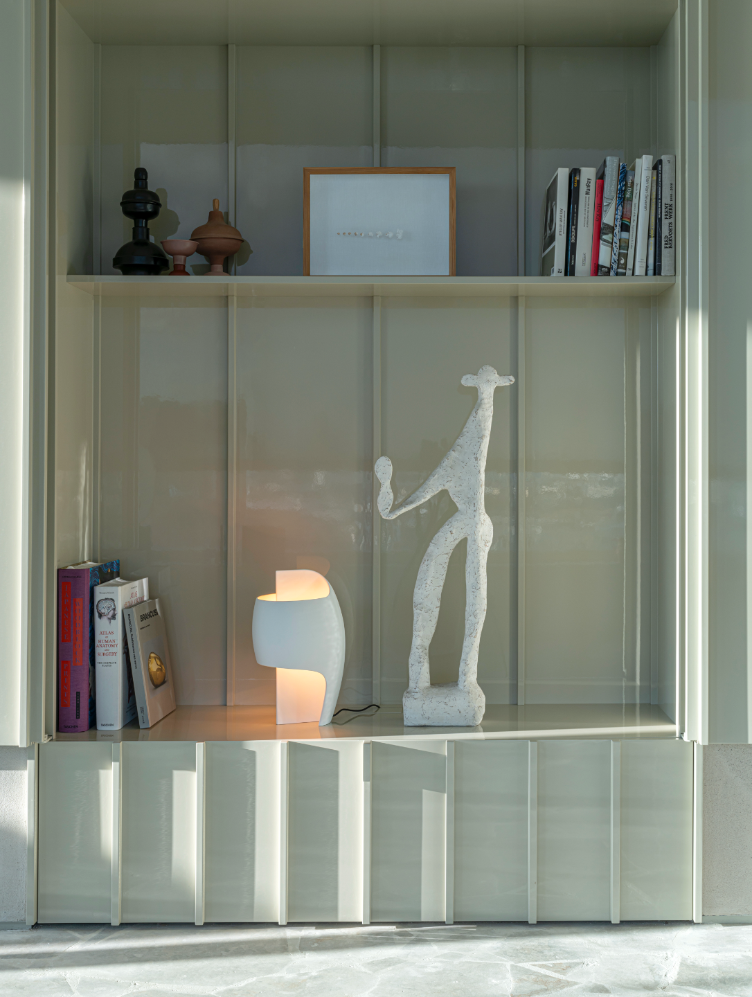 Modern interior with a shelf displaying books, a lamp, and decorative items.