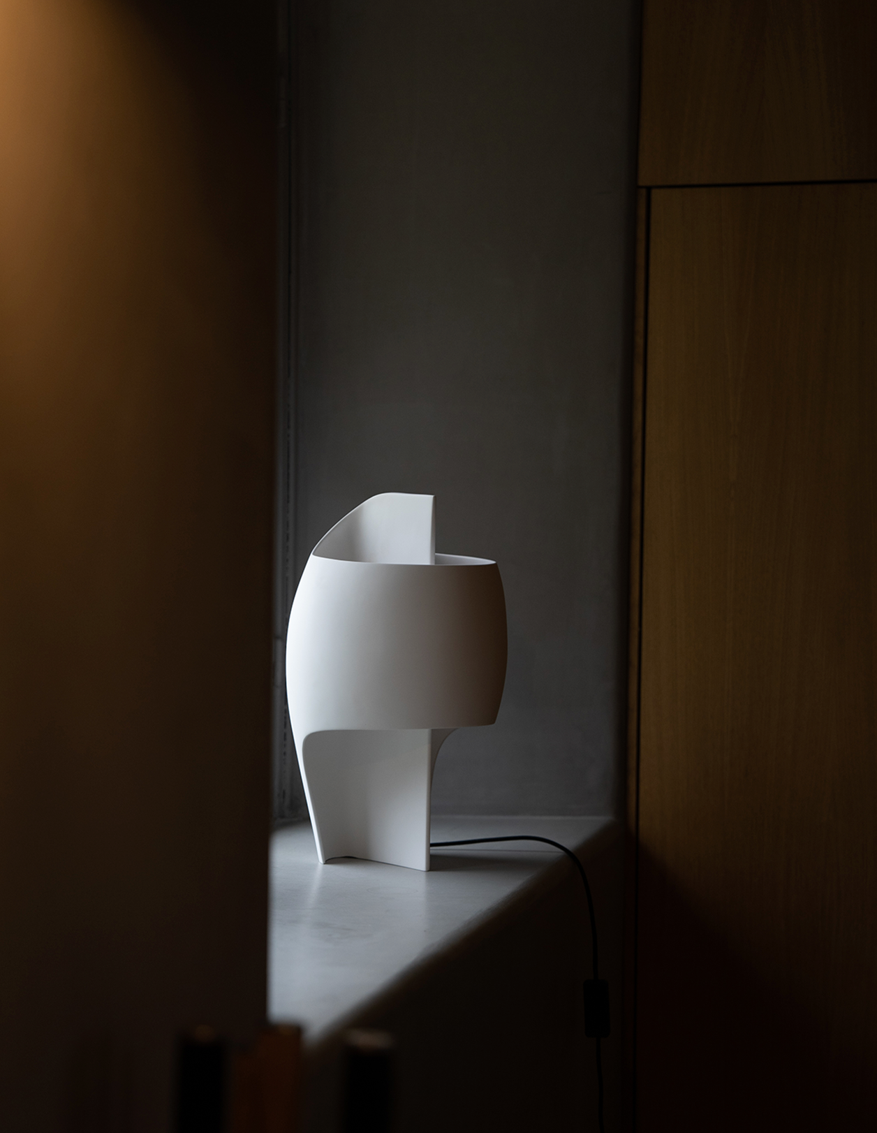 Modern white table lamp on a dark surface with a neutral background