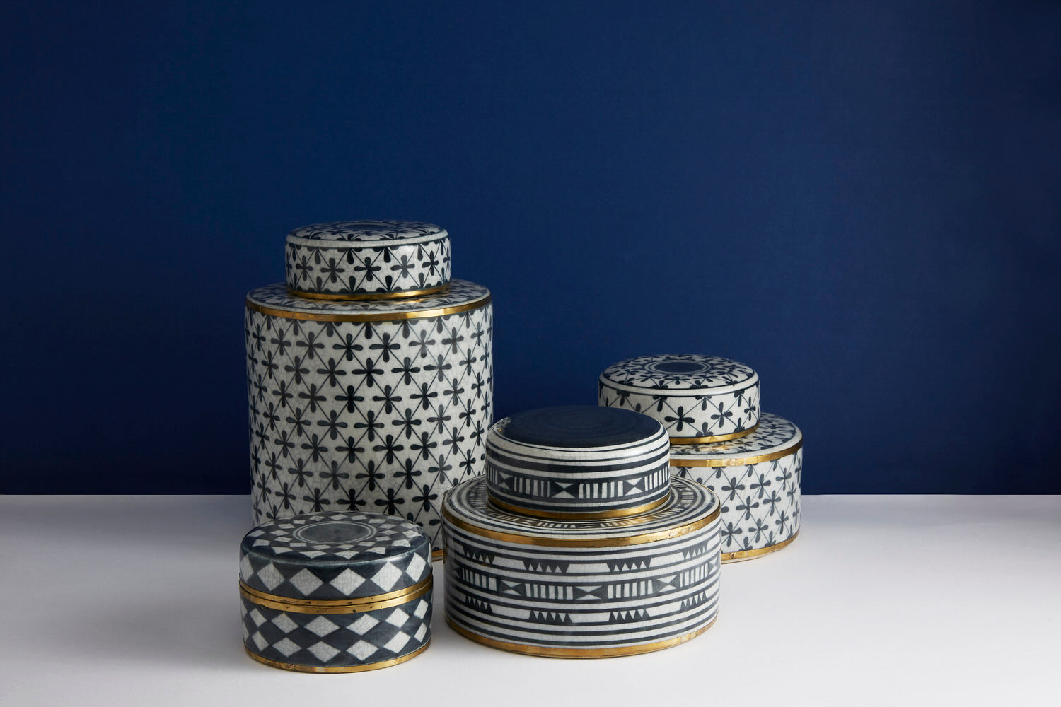 Set of decorative tins with geometric patterns on a white surface against a dark blue background