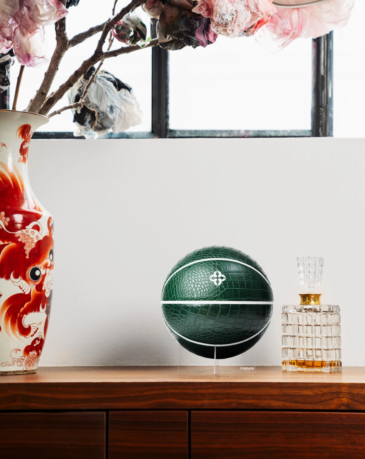 Green basketball on a white surface with decorative vases and flowers in the background