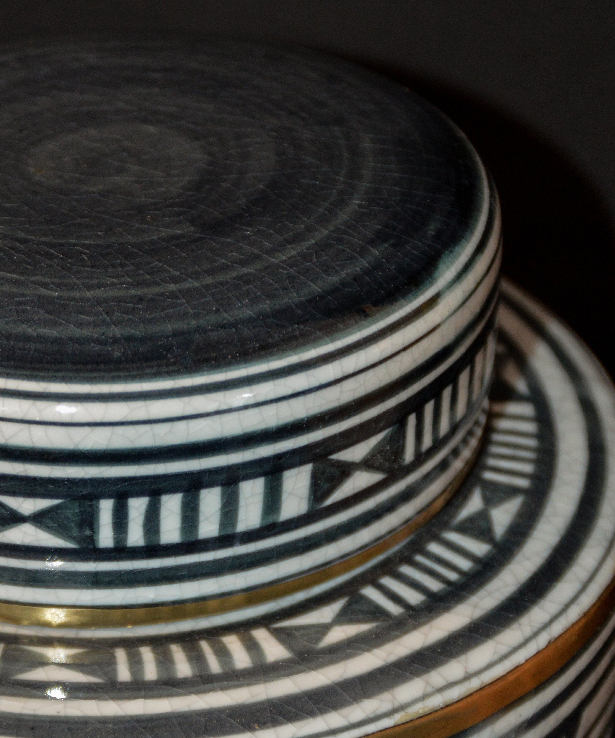 Close-up of a ceramic container with geometric patterns on a dark background