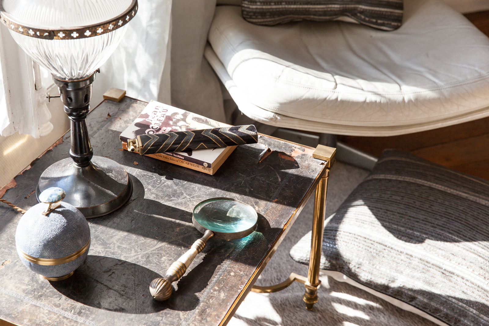Decorative table with a lamp, books, and small objects in a cozy room.