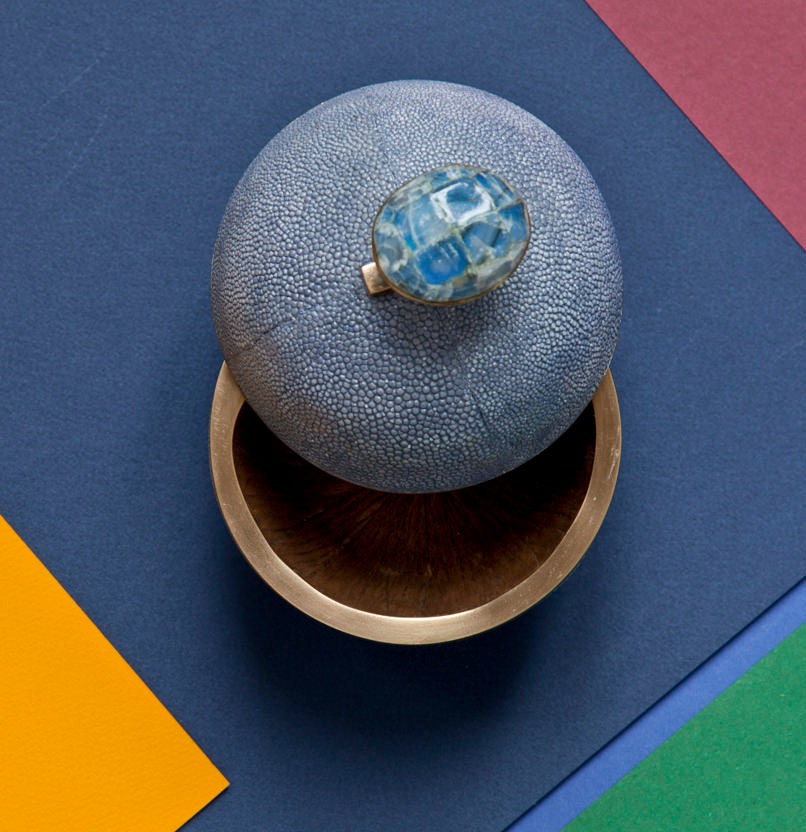 Decorative object with textured surface and blue gemstone on a multicolored background