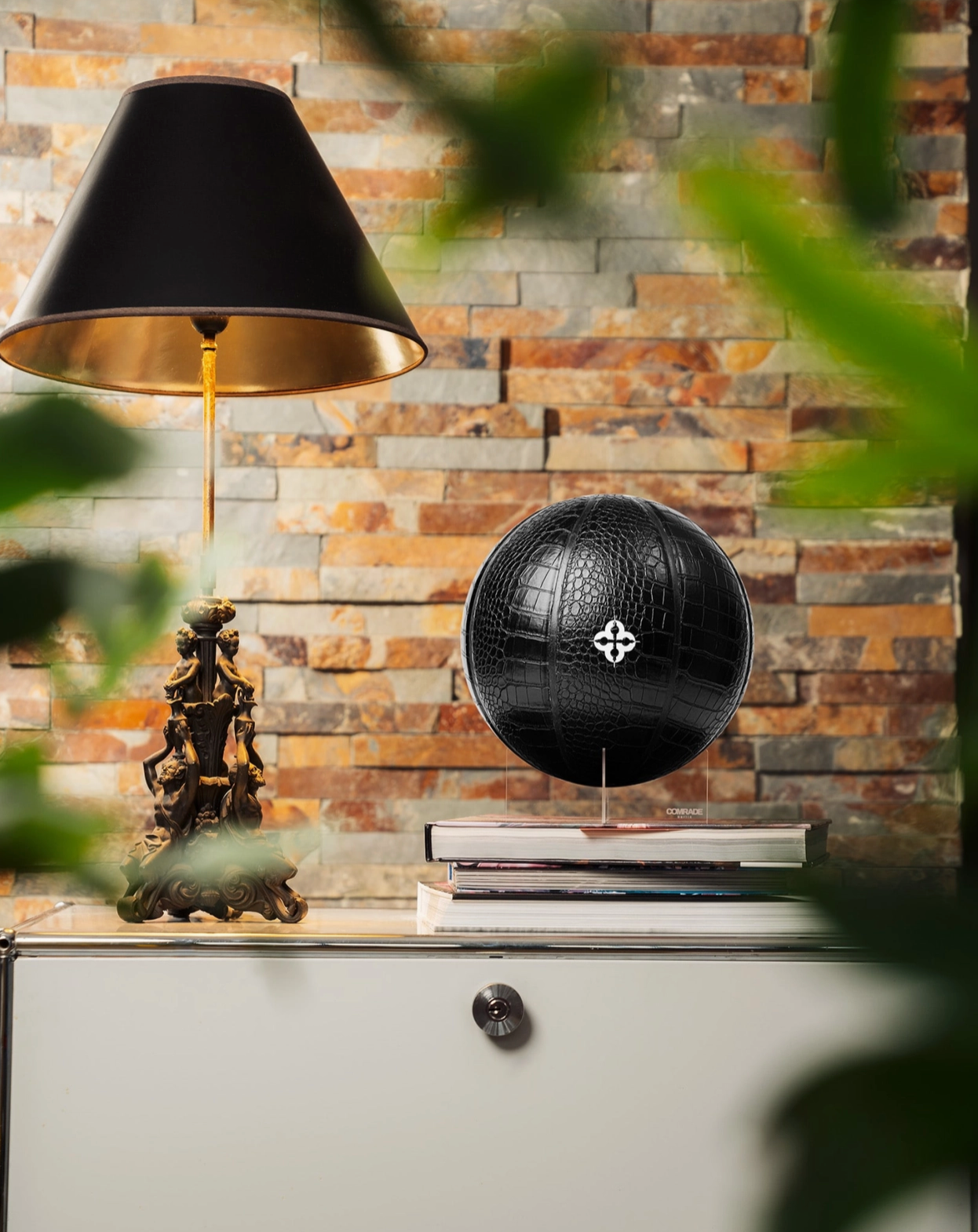 Black globe on a shelf with decorative items against a stone wall.