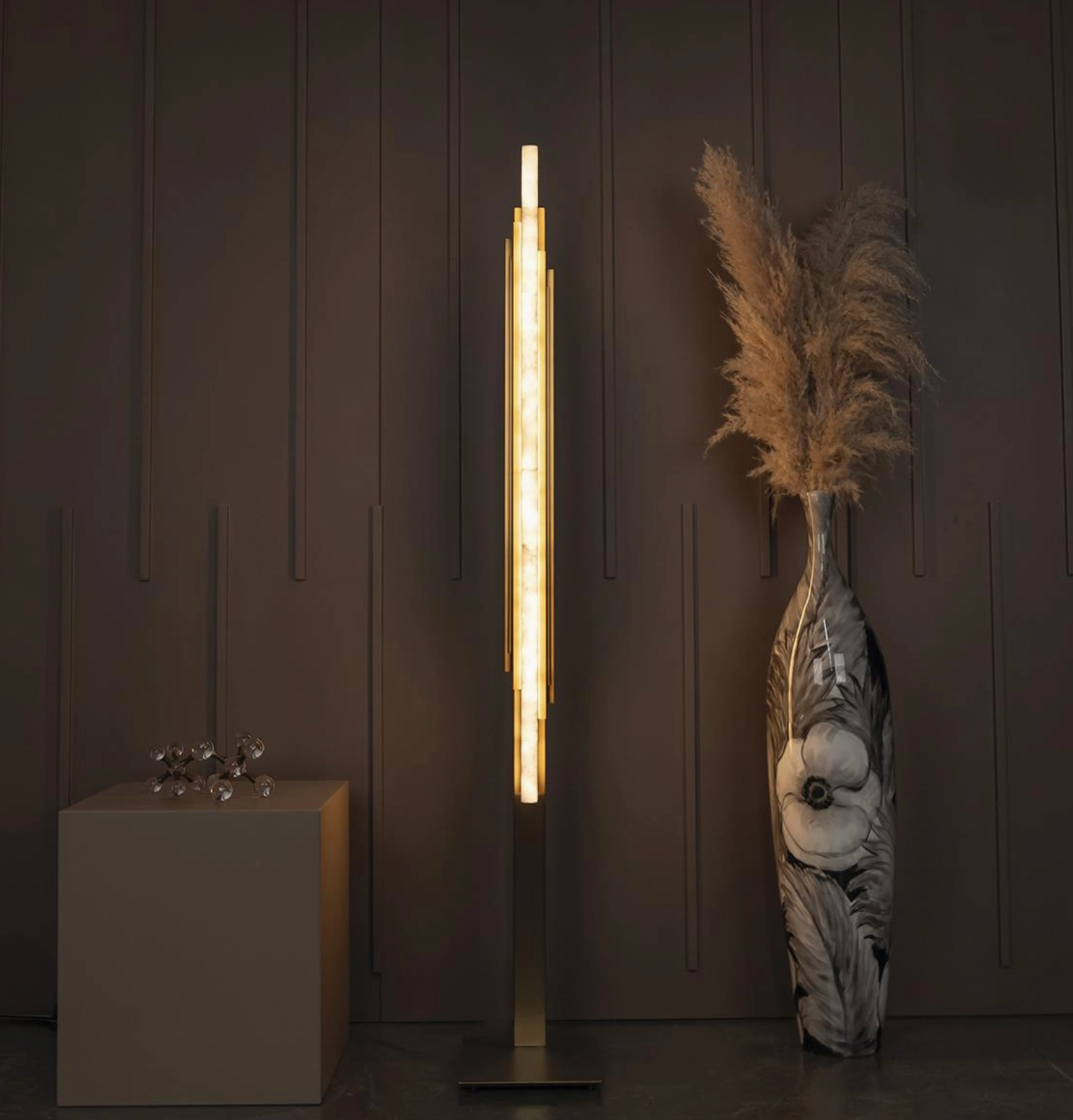Modern floor lamp with decorative vase and abstract sculpture against a dark wall.
