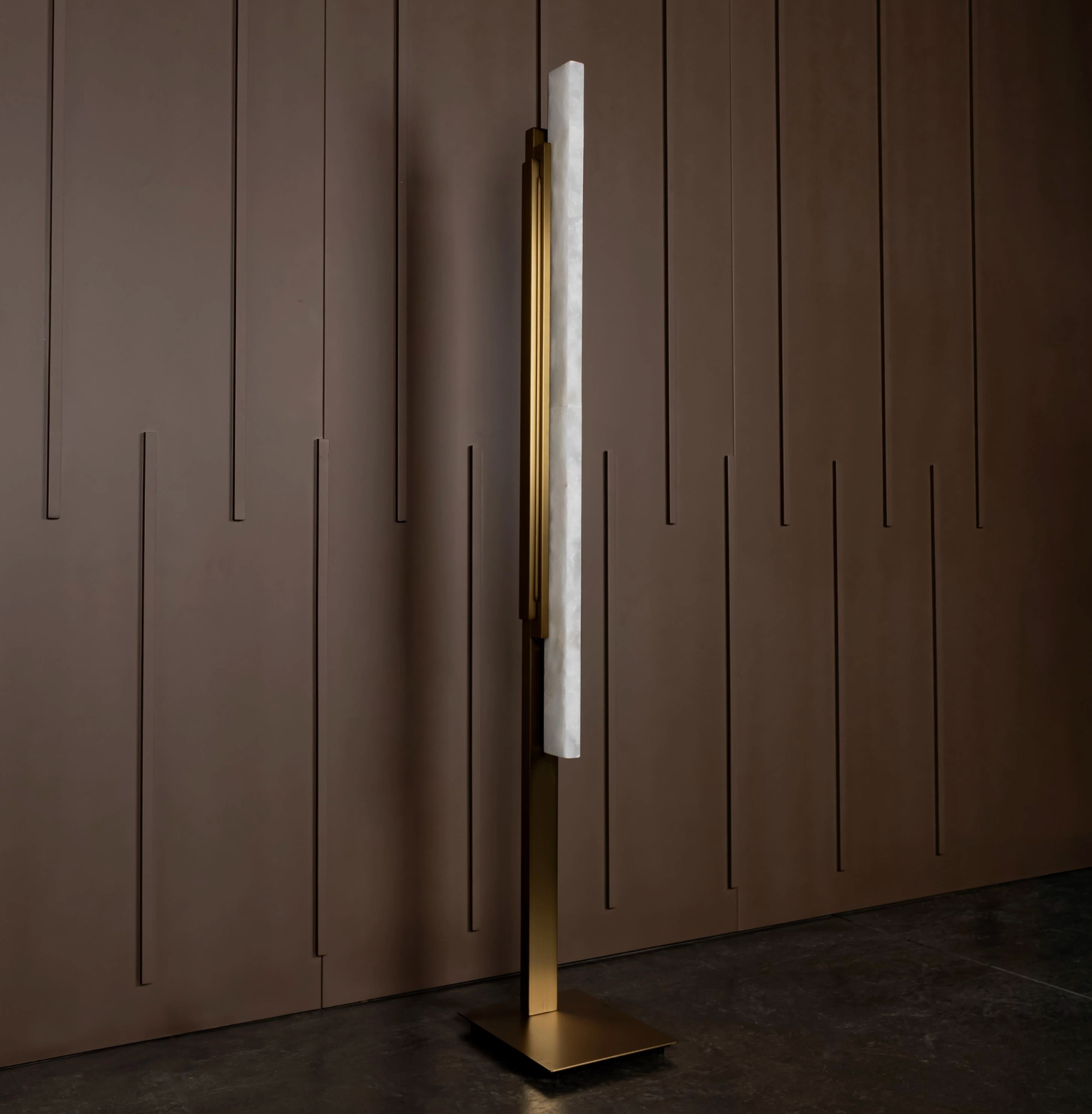 Modern floor lamp with marble base and gold accents against a brown paneled wall.