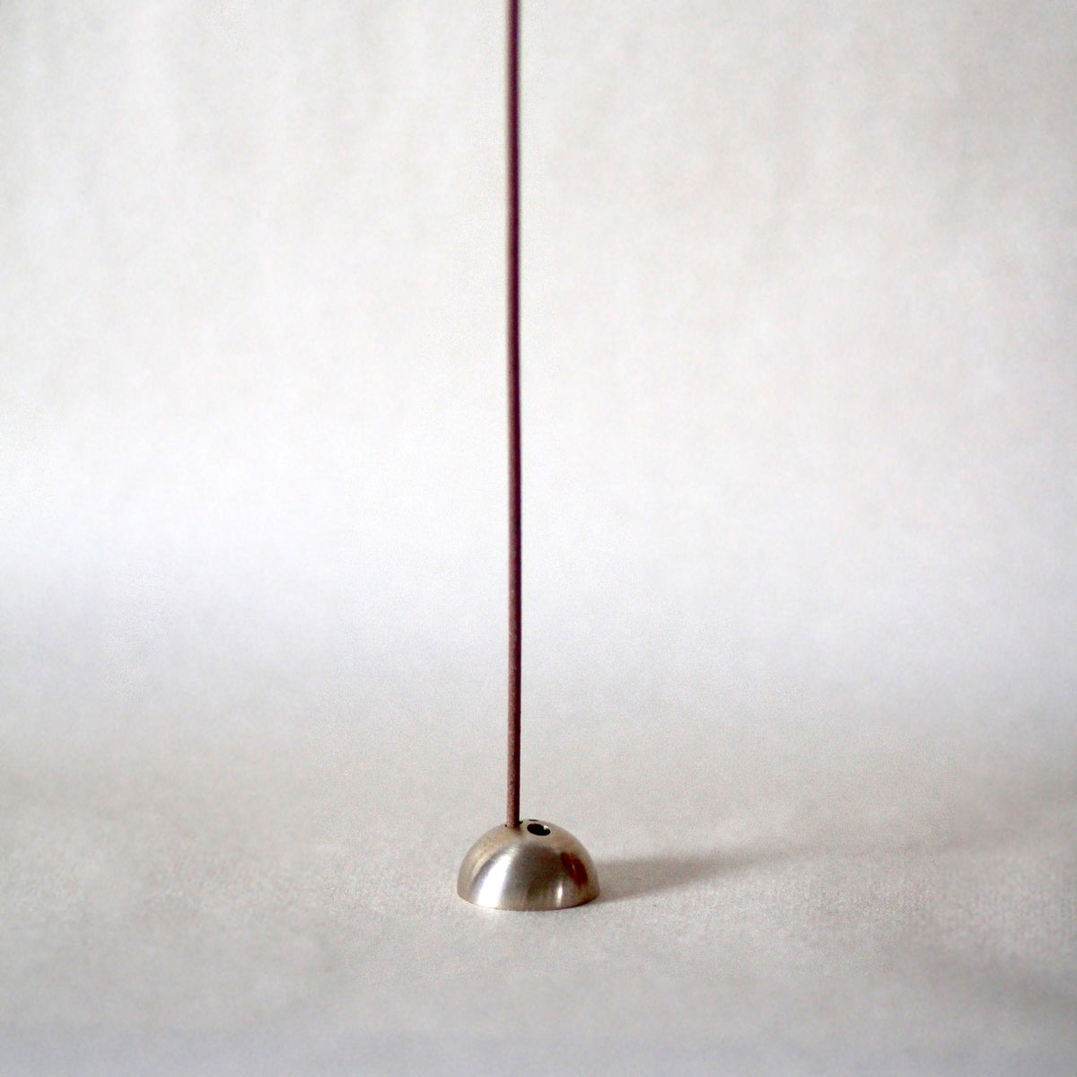 Metallic floor lamp with a long thin neck on a white background