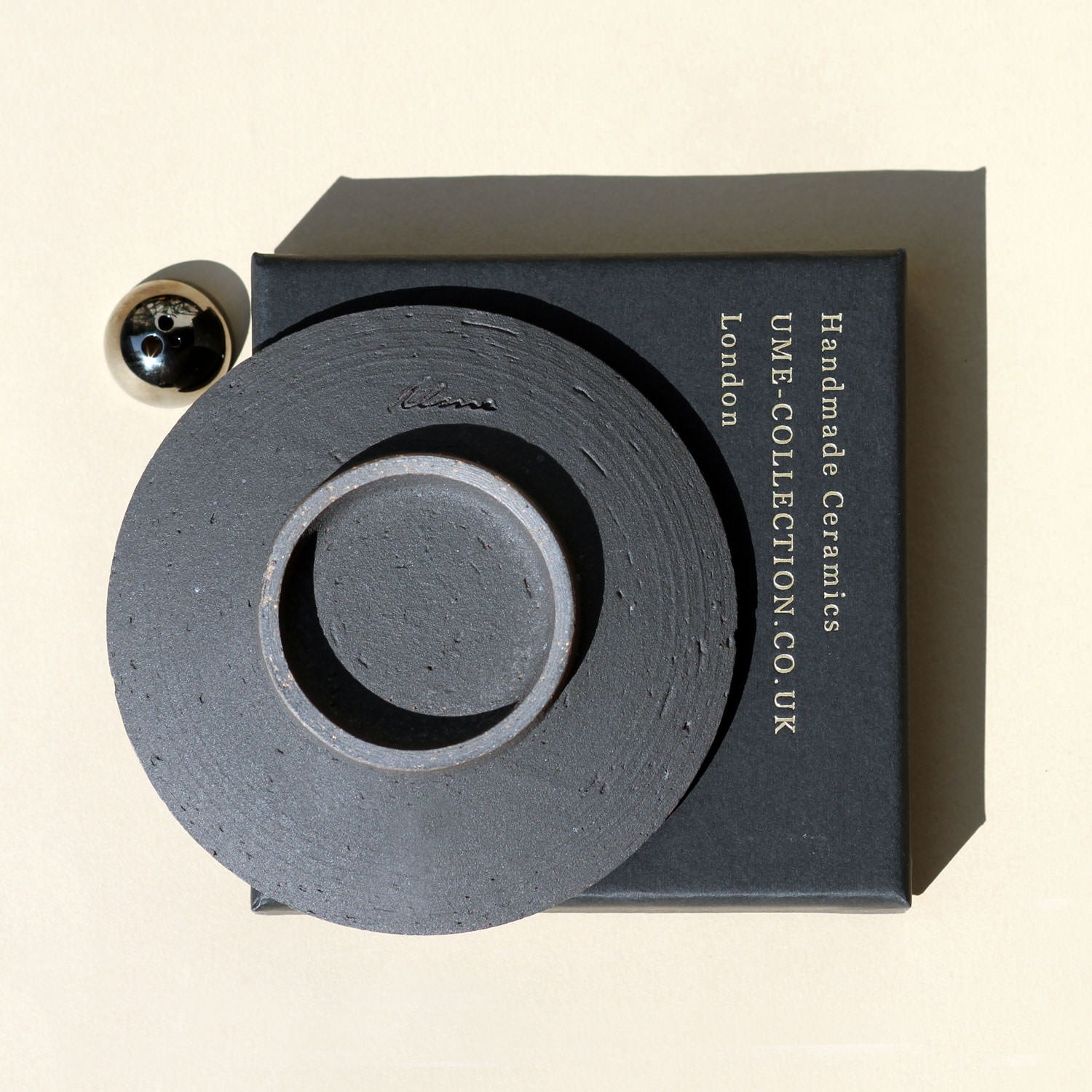 Ceramic piece with 'UME Collection' branding on a beige background