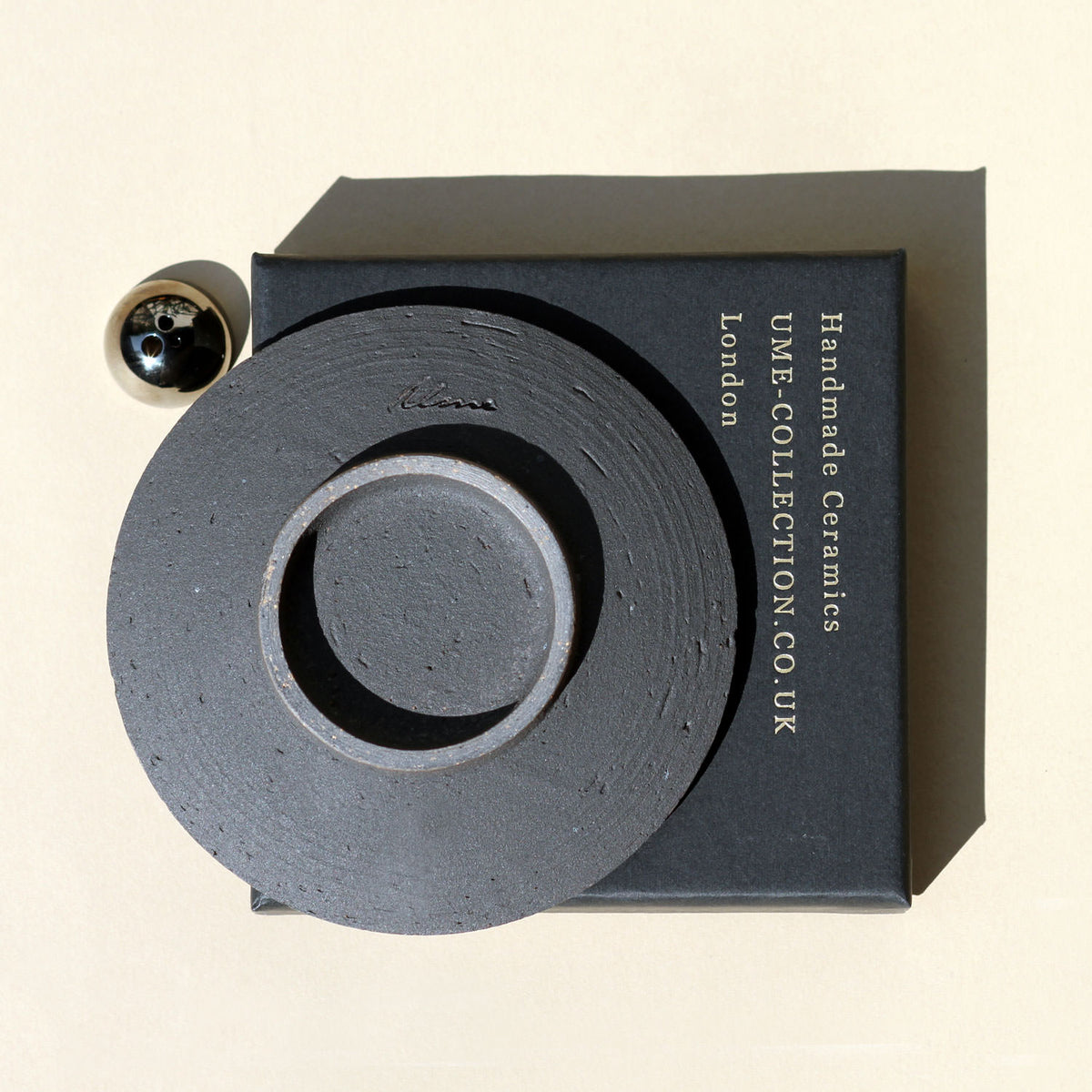 Ceramic piece with 'UME Collection' branding on a beige background