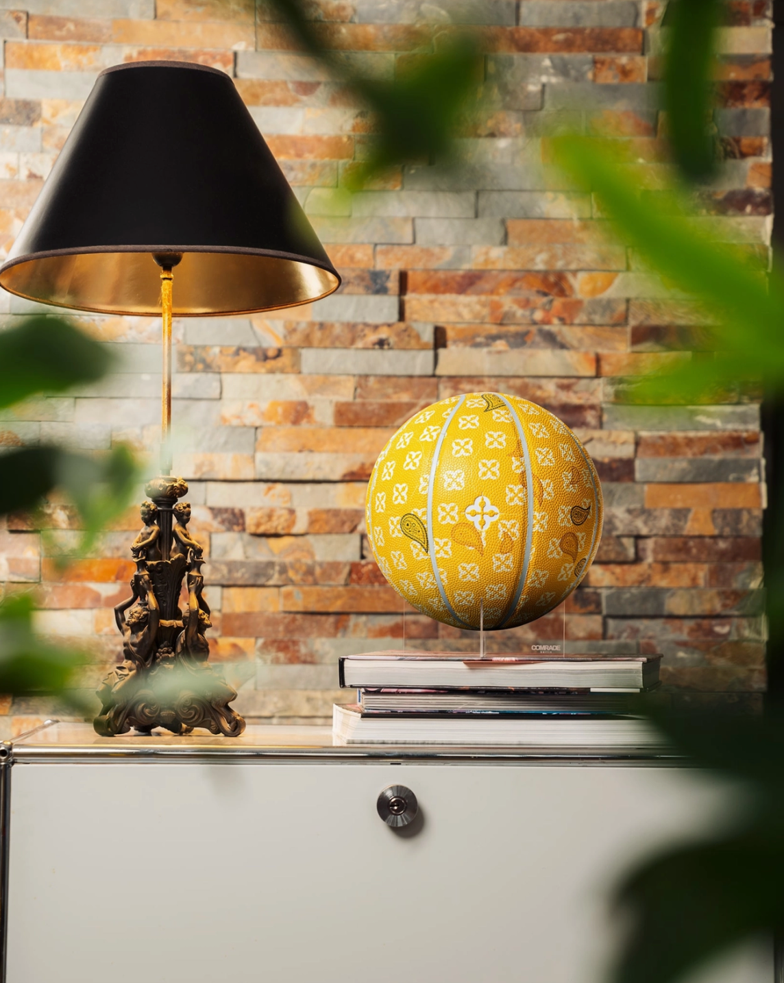 Decorative yellow sphere with patterns on a shelf against a stone wall.