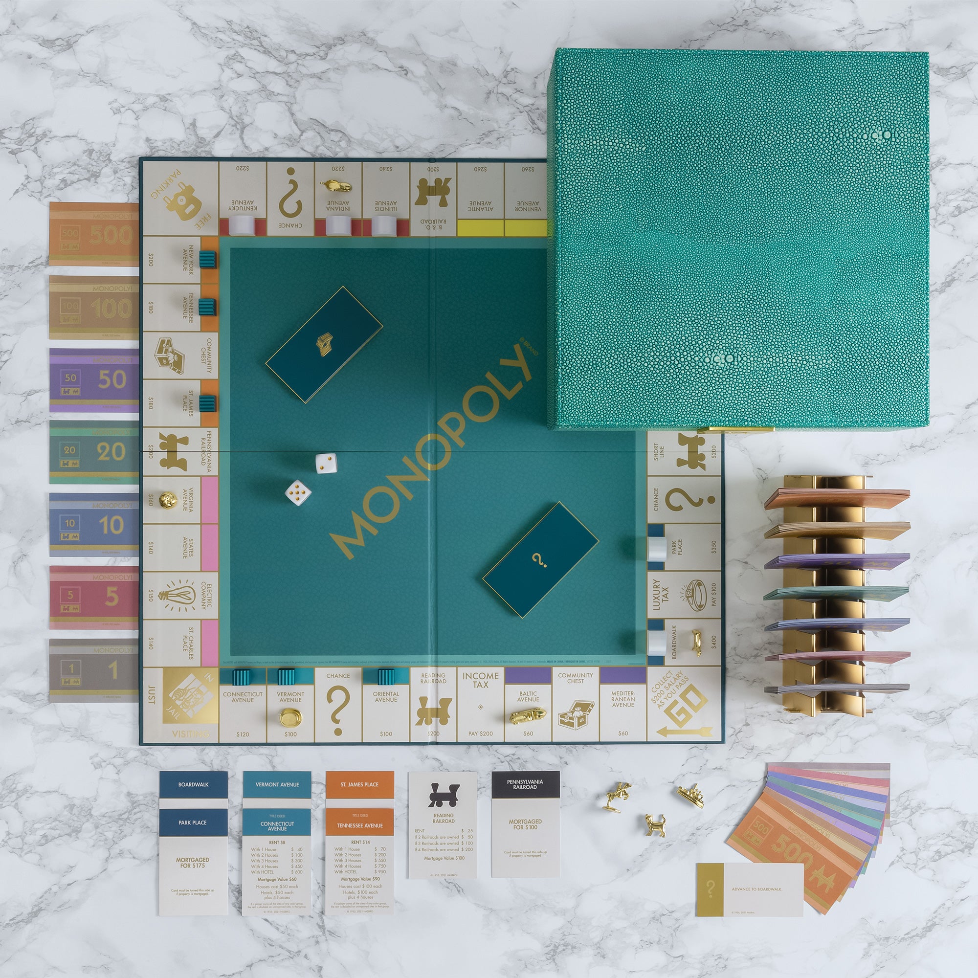 Monopoly game set with teal board and cards on a marble surface