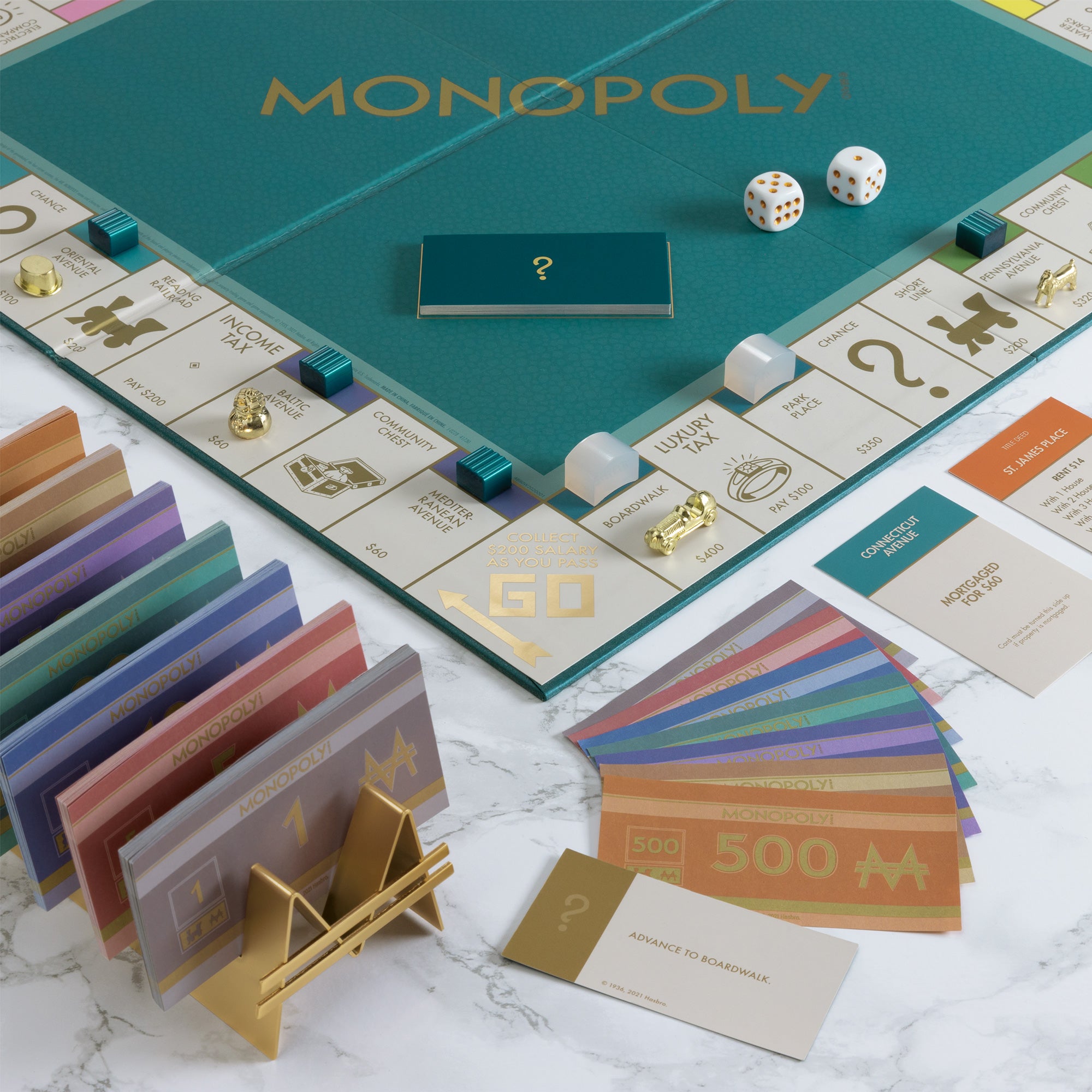 Monopoly game board with cards and dice on a marble surface