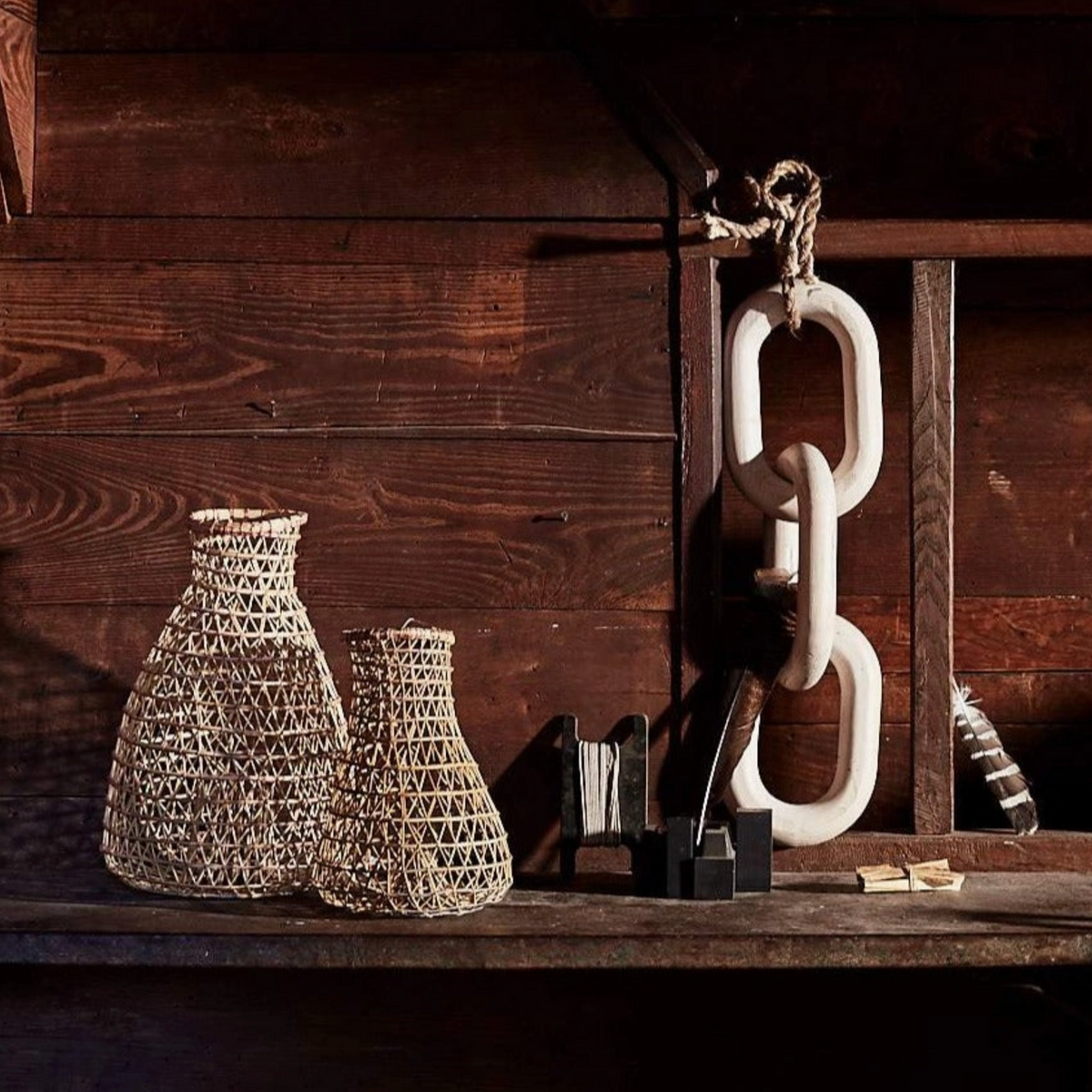 Decorative vases and chain on a wooden shelf with a rustic background