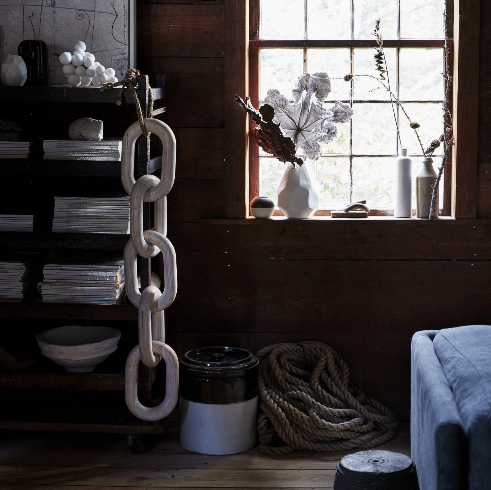 Decorative chain hanging in a room with a window, books, and a plant.