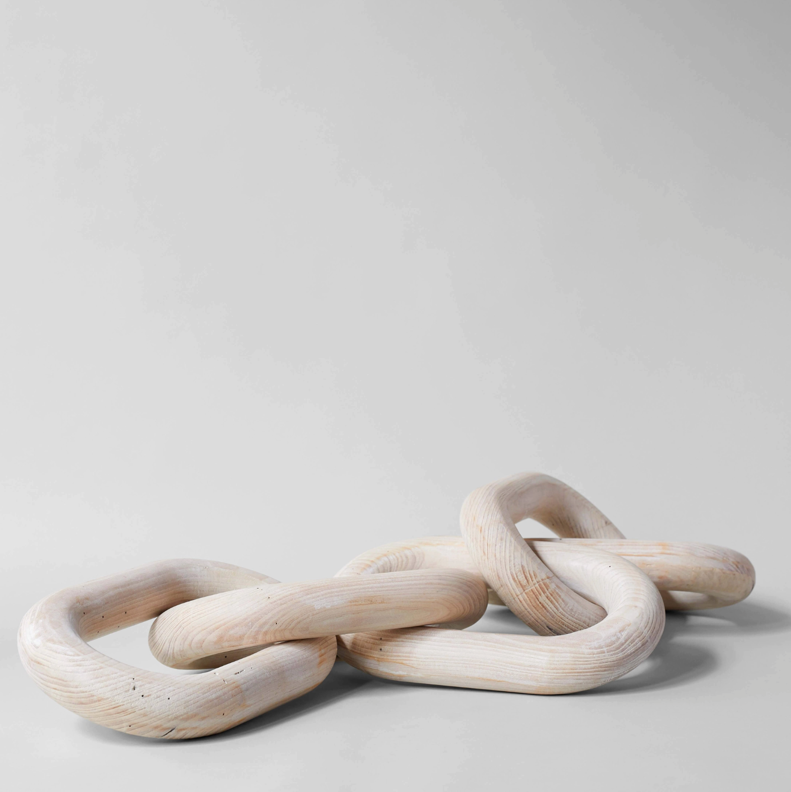 Three interlinked wooden rings on a light gray background