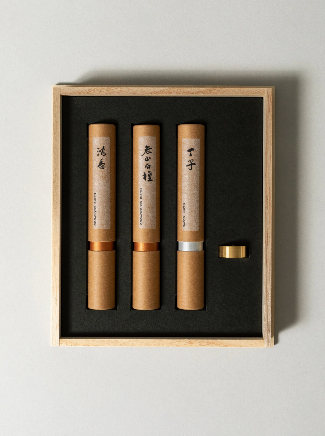 Three cylindrical products with labels in a wooden box on a light gray background