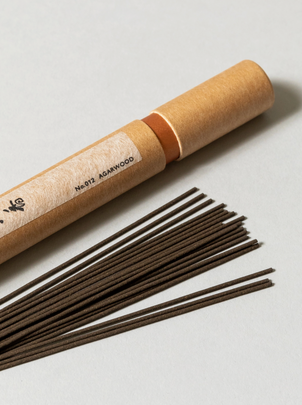 Incense sticks with a cardboard tube on a light background
