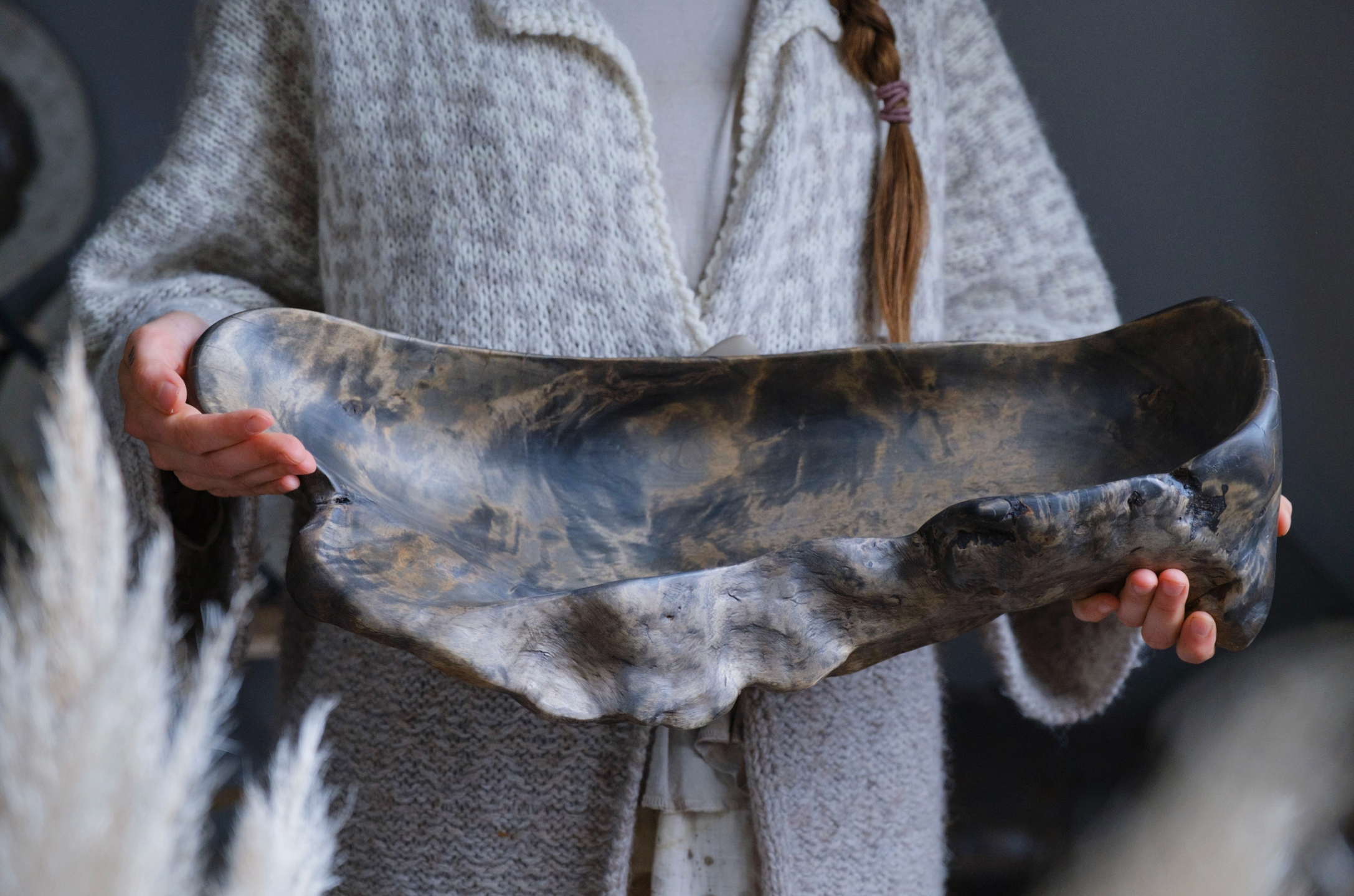 Person holding a large, ancient-looking stone bowl with a textured surface.