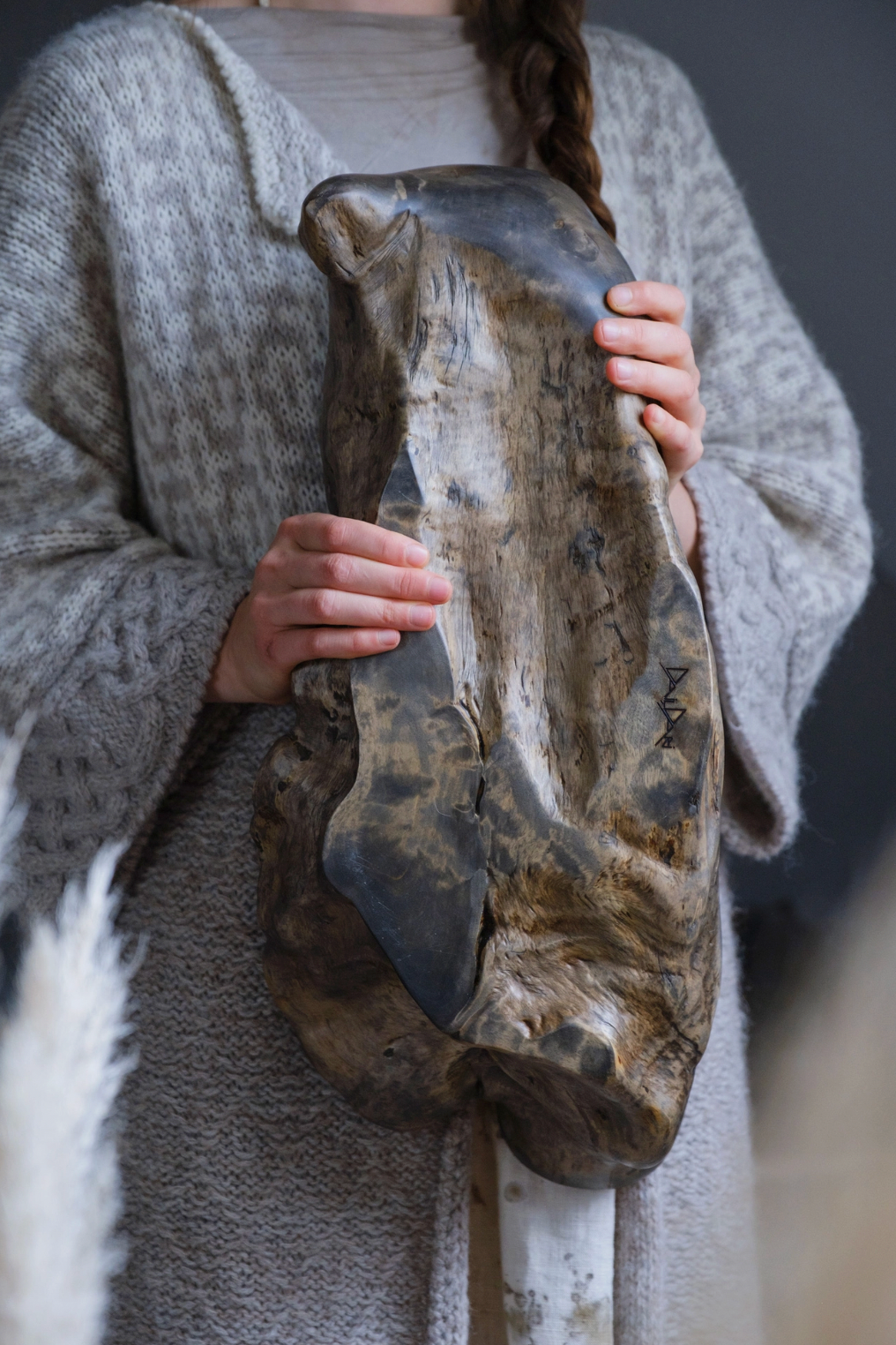Person holding a large, textured stone against a blurred background