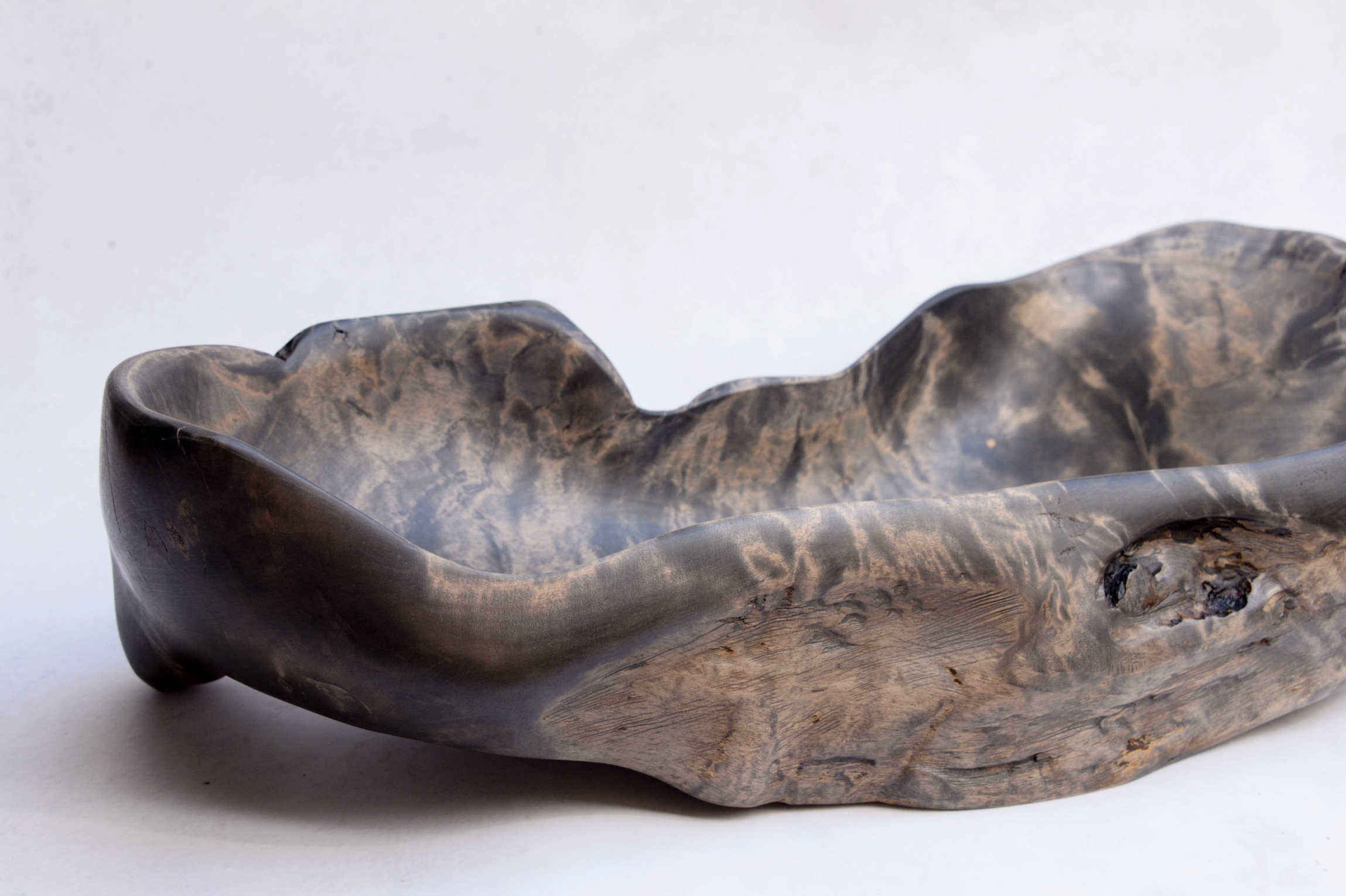 Wooden bowl with a natural, wavy design on a white background