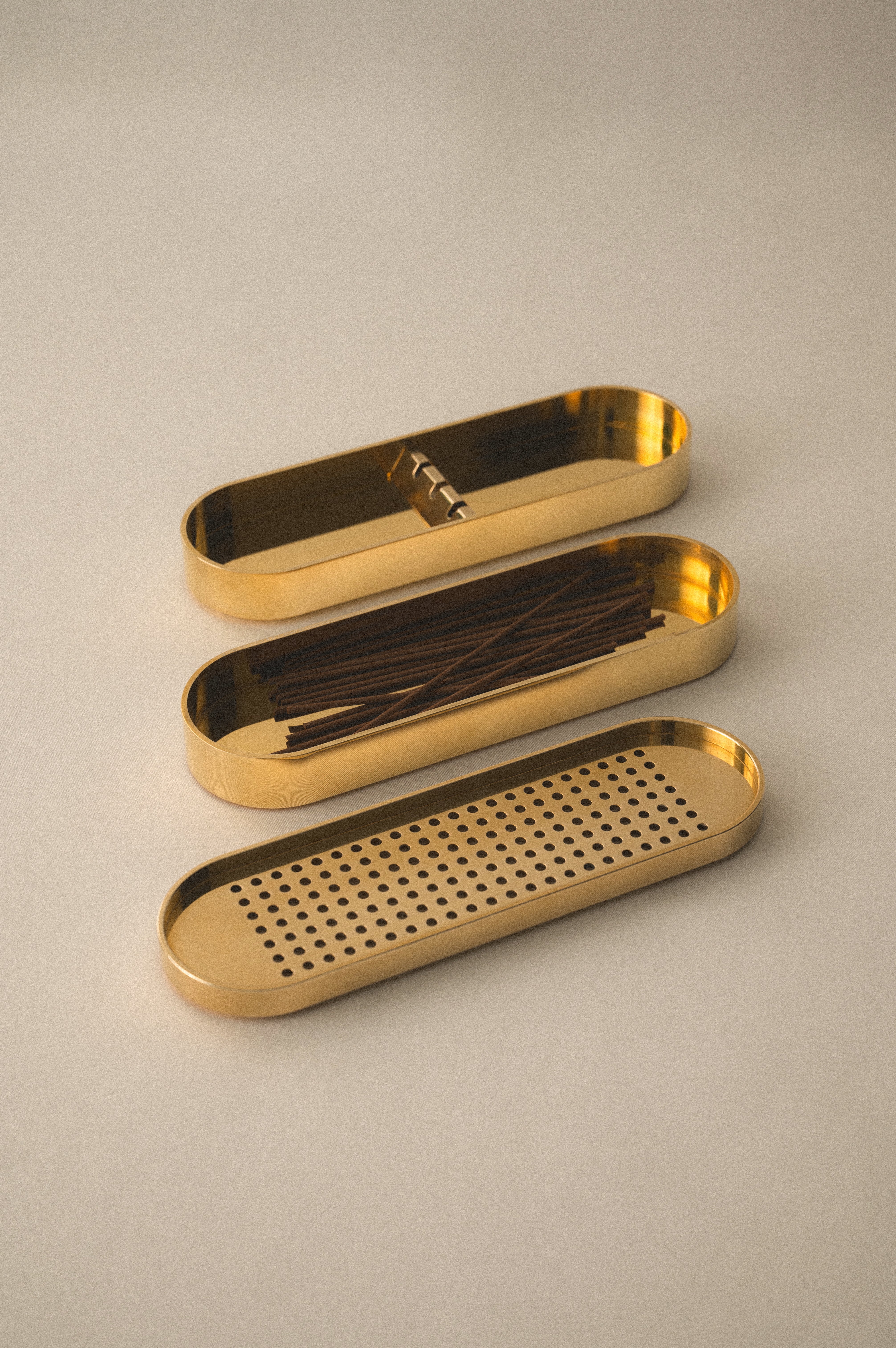 Brass Incense Burner . Set of three gold trays on a beige background