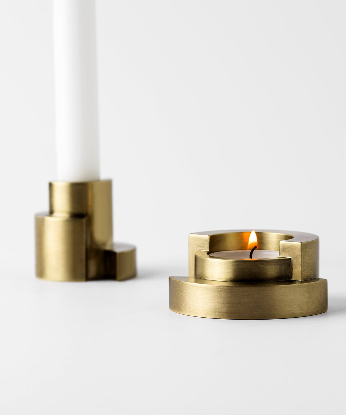 Brass candle holders with a lit candle on a white background