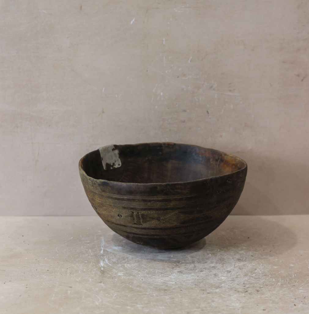 Vintage wooden bowl on a textured surface with a neutral background