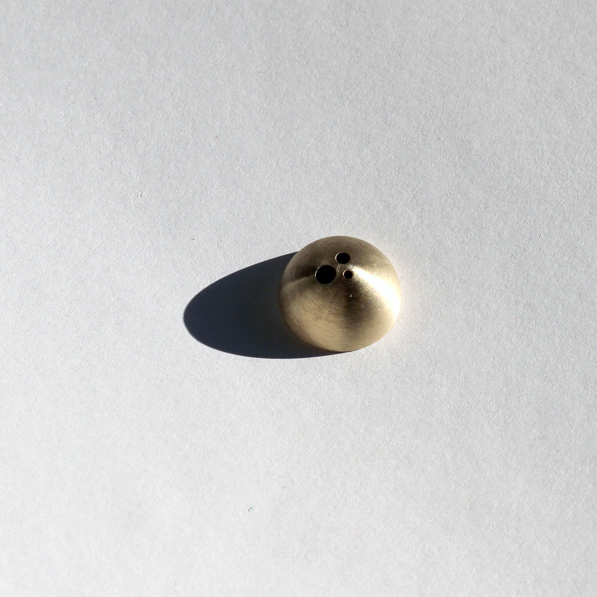 Brass-colored object on a light gray background