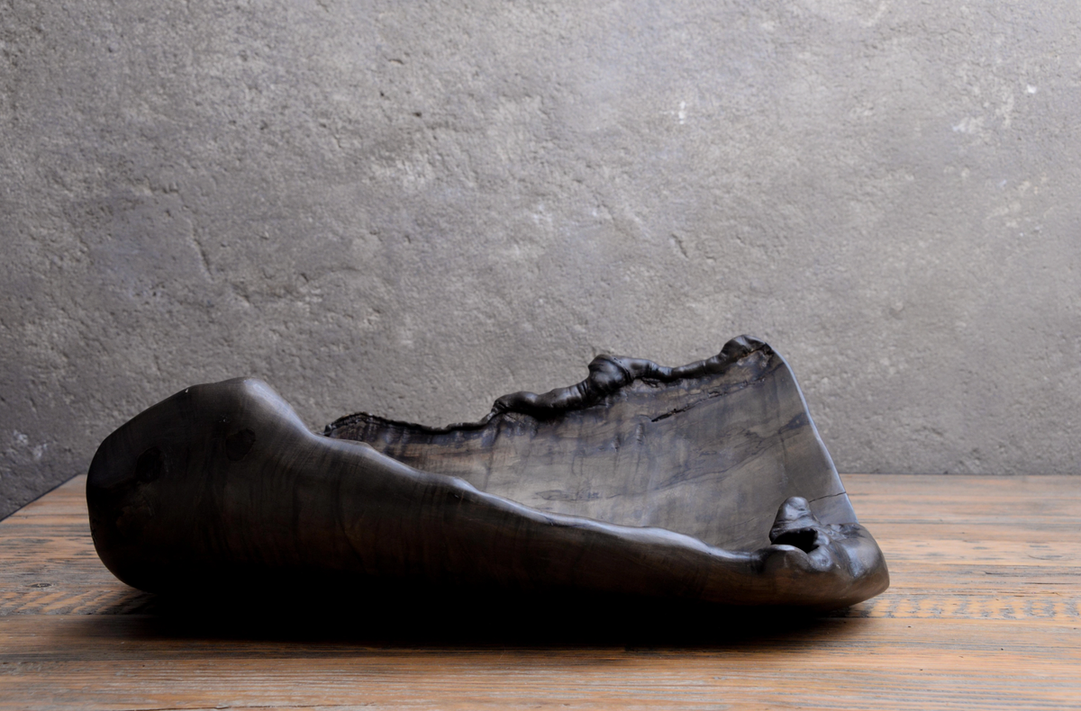 Black stone sculpture on a wooden surface with a gray background