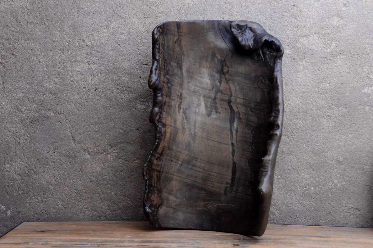 Rustic wooden cutting board on a wooden surface with a gray concrete wall background